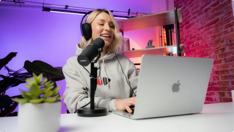 Blond woman smiling and recording a podcast with a microphone, macbook and audio interface in a recording studio - Audio Interface for Podcasting